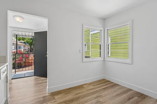 a view of an empty room with wooden floor and a window