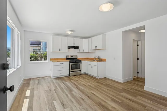 a kitchen with granite countertop a refrigerator cabinets and wooden floor