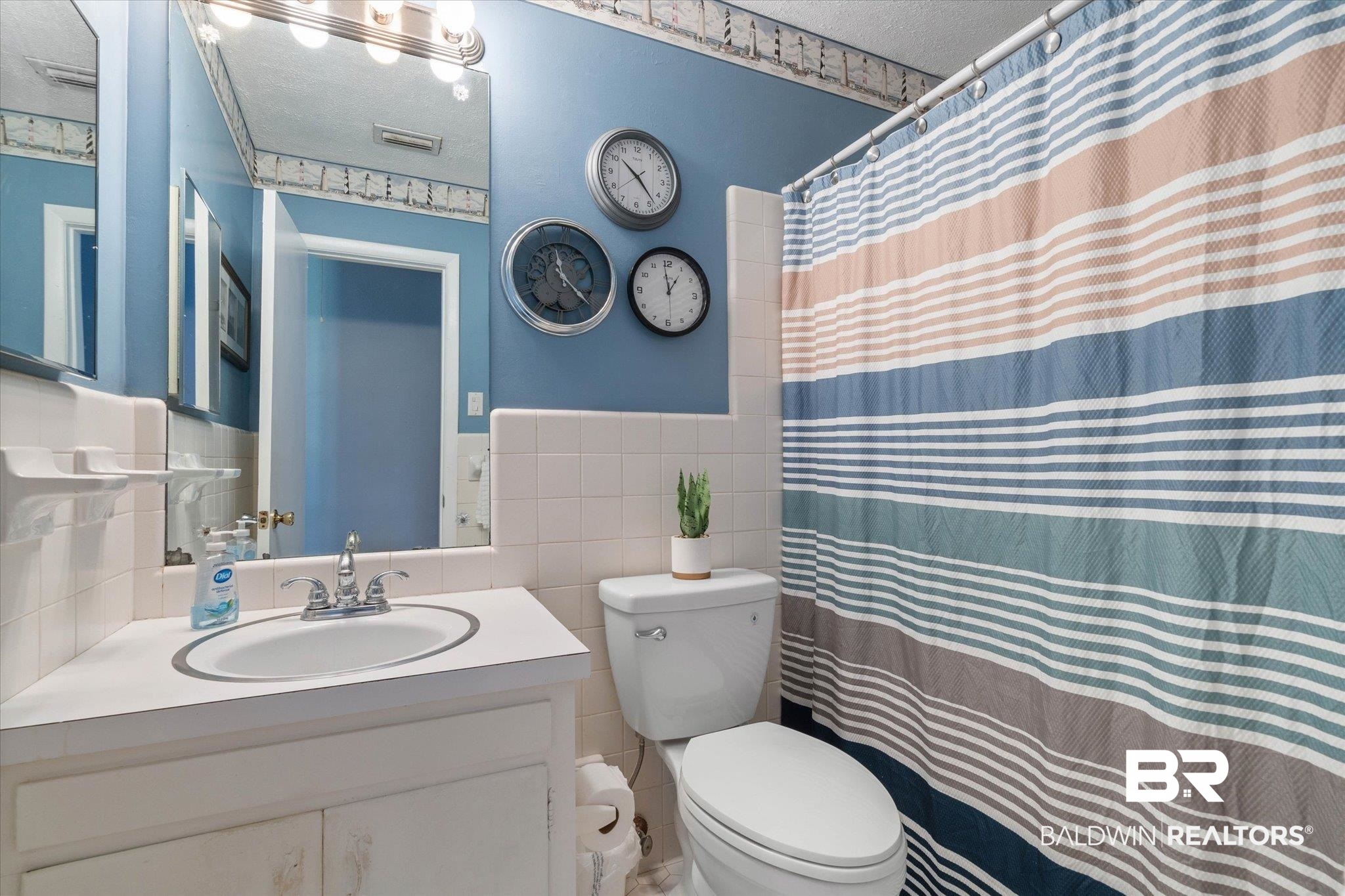 706 Sutherland Drive Chickasaw, AL 36611 - Photo 18 of 33 Bathroom featuring tile walls, visible vents, toilet, and wainscoting