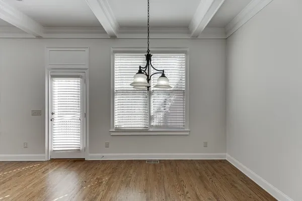 a view of an empty room with wooden floor fireplace and a window