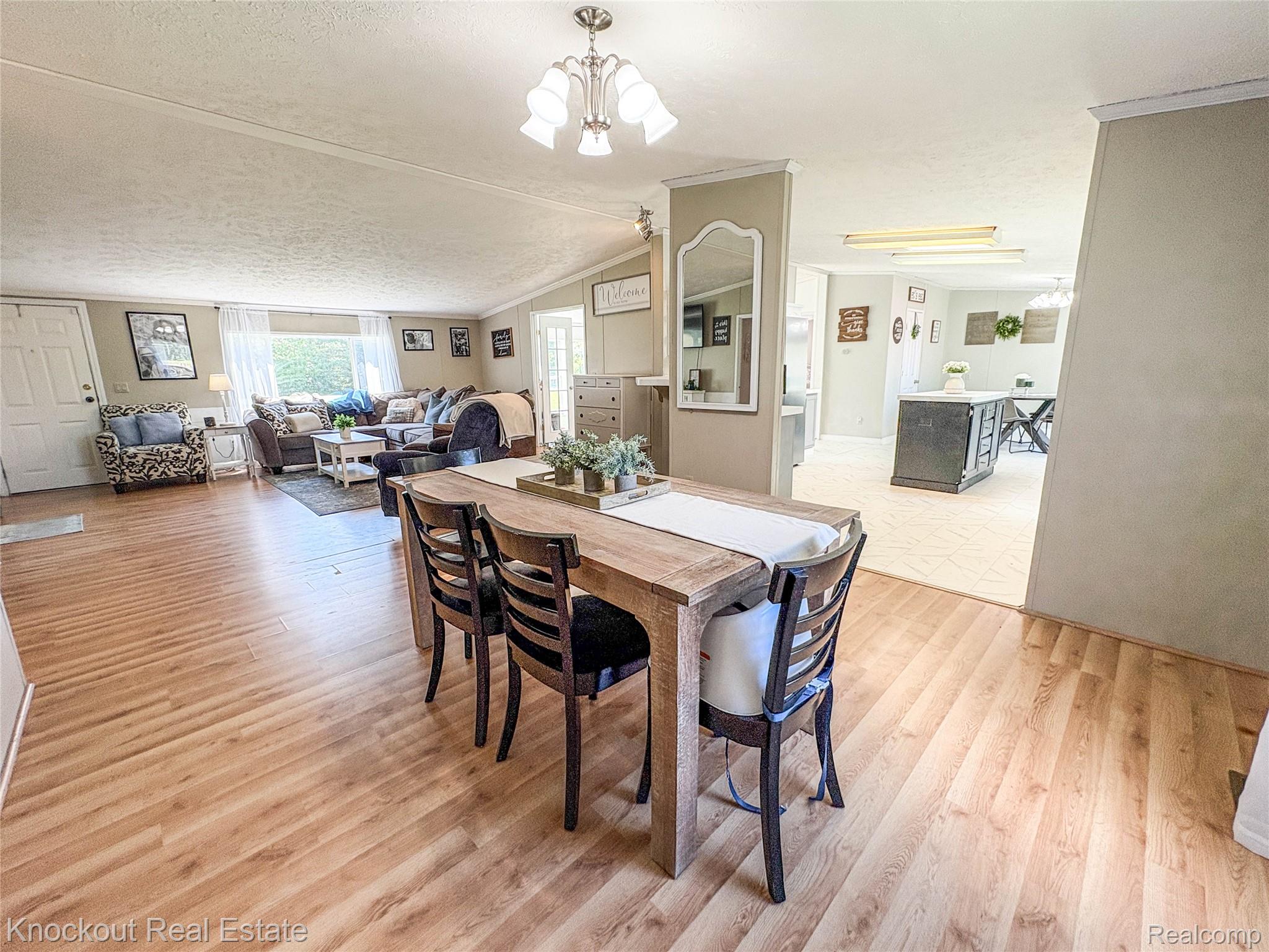 7760 Bell Road Birch Run, MI 48415 - Photo 8 of 68 Dining area featuring wood-finish flooring, a chandelier light fixture, and an open concept layout connecting to a living area and a kitchen with tiled flooring