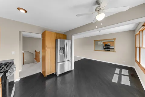 an empty room with wooden floor chandelier fan and windows