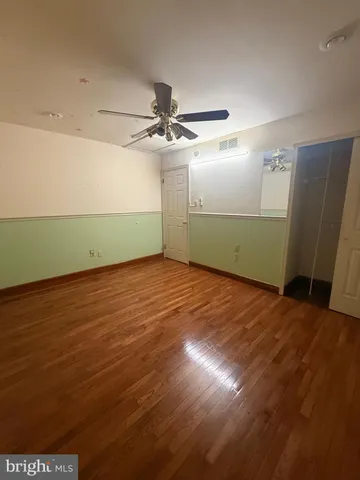 an empty room with wooden floor and fan