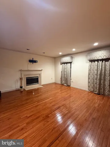 a view of empty room with wooden floor and fireplace