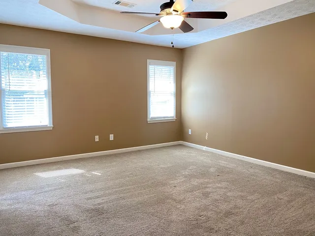an empty room with windows and fan