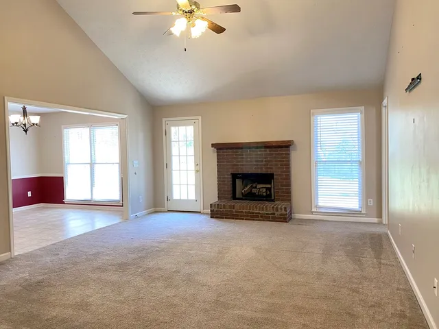 an empty room with windows and fireplace