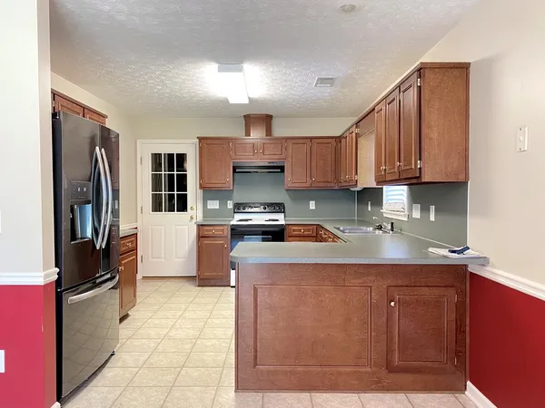 a kitchen with stainless steel appliances granite countertop a refrigerator a sink a stove and oven