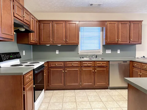a kitchen with granite countertop a sink cabinets and stainless steel appliances