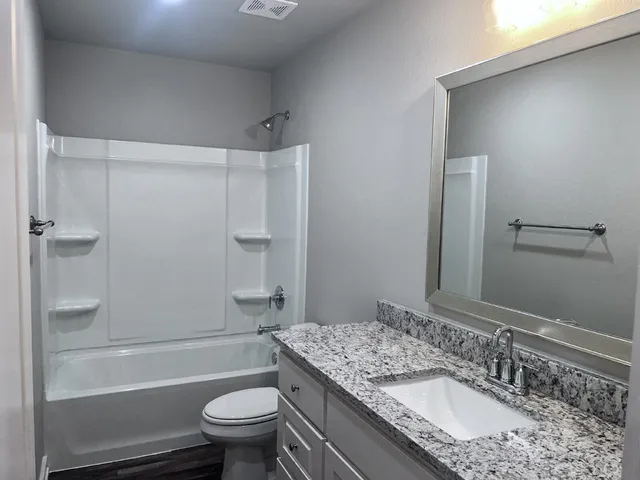 a bathroom with a granite countertop sink toilet and shower