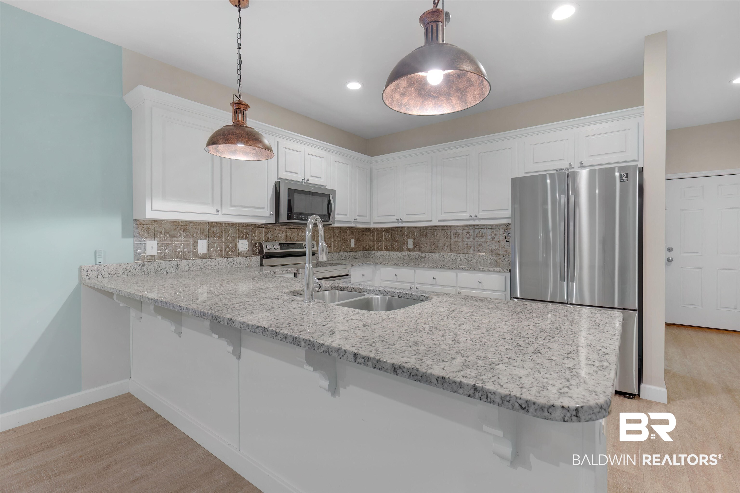 5625 Georgia Street Orange Beach, AL 36561 - Photo 12 of 30 Kitchen featuring appliances with stainless steel finishes, hanging light fixtures, kitchen peninsula, decorative backsplash, and white cabinets