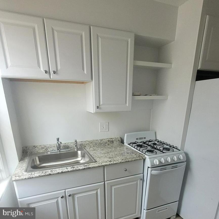 3731 Bonview Avenue, Unit 2B Baltimore, MD 21213 - Photo 3 of 14 a kitchen with granite countertop white cabinets and white appliances