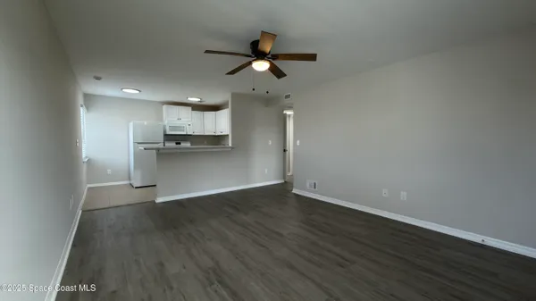 a view of a kitchen with a sink a ceiling fan and stainless steel appliances