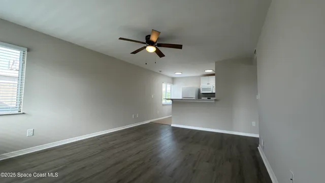 an empty room with wooden floor ceiling fan and windows