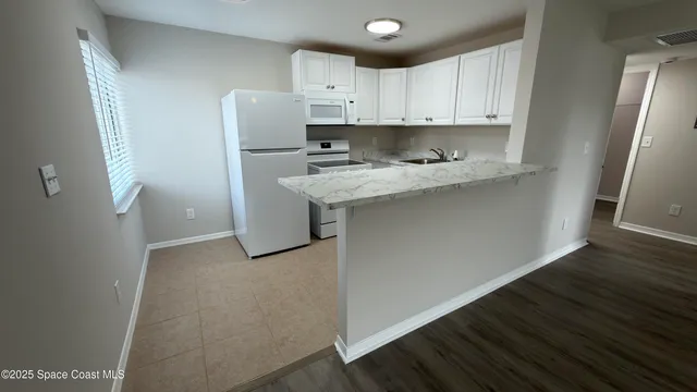 a kitchen with stainless steel appliances granite countertop a refrigerator sink and white cabinets
