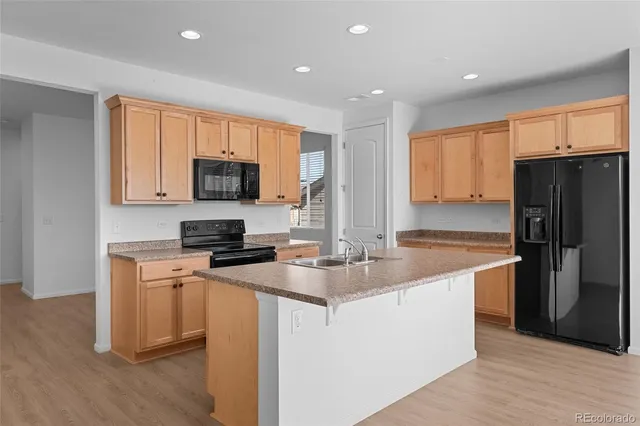 a kitchen with stainless steel appliances granite countertop a stove a refrigerator a sink a oven with wooden cabinets and wooden floor