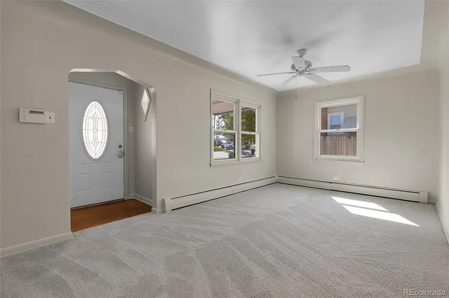 an empty room with windows and fan