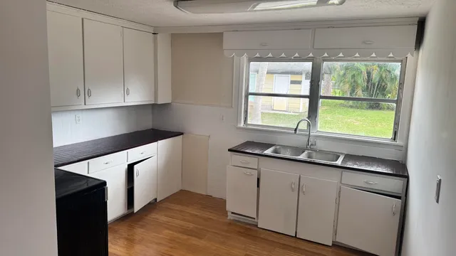 a kitchen with stainless steel appliances granite countertop white cabinets and a window