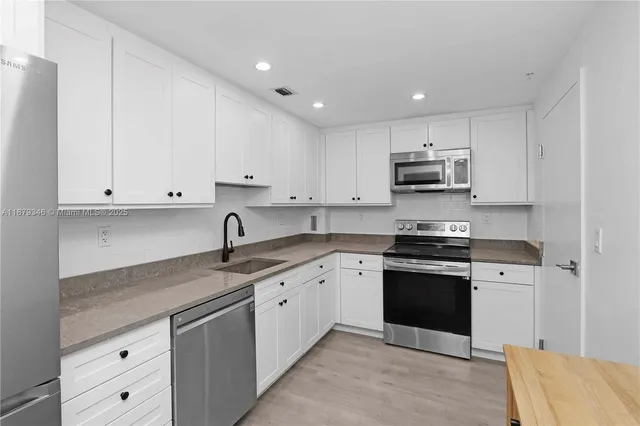 a kitchen with stainless steel appliances granite countertop a sink and dishwasher a stove top oven with white cabinets