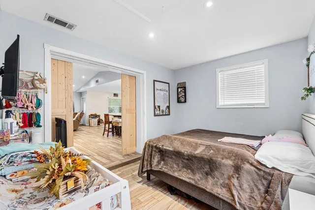 a bedroom with a bed a dresser and flat screen tv