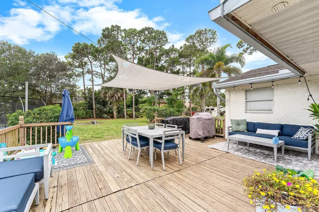 a view of a patio with a dining table and chairs with wooden floor and fence