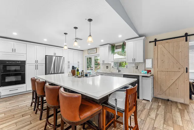a kitchen with stainless steel appliances granite countertop a stove a refrigerator a kitchen island a table and chairs