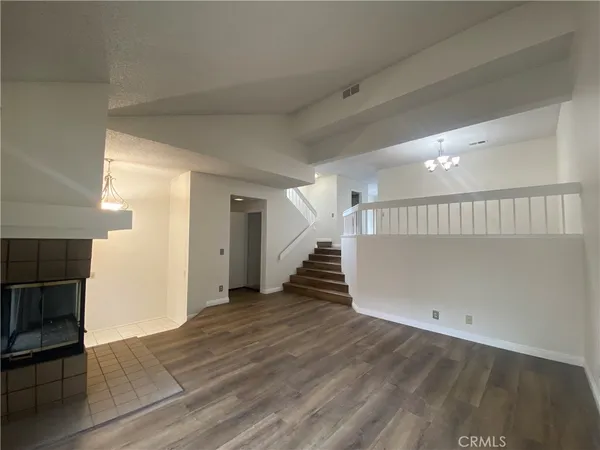 a view of an empty room with wooden floor fireplace and a window
