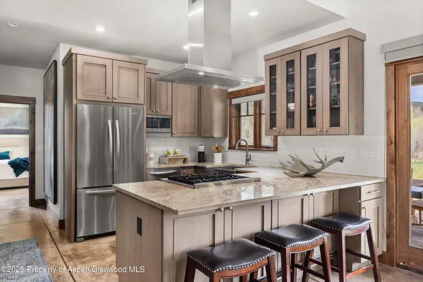 a kitchen with granite countertop a refrigerator stove top oven and cabinets