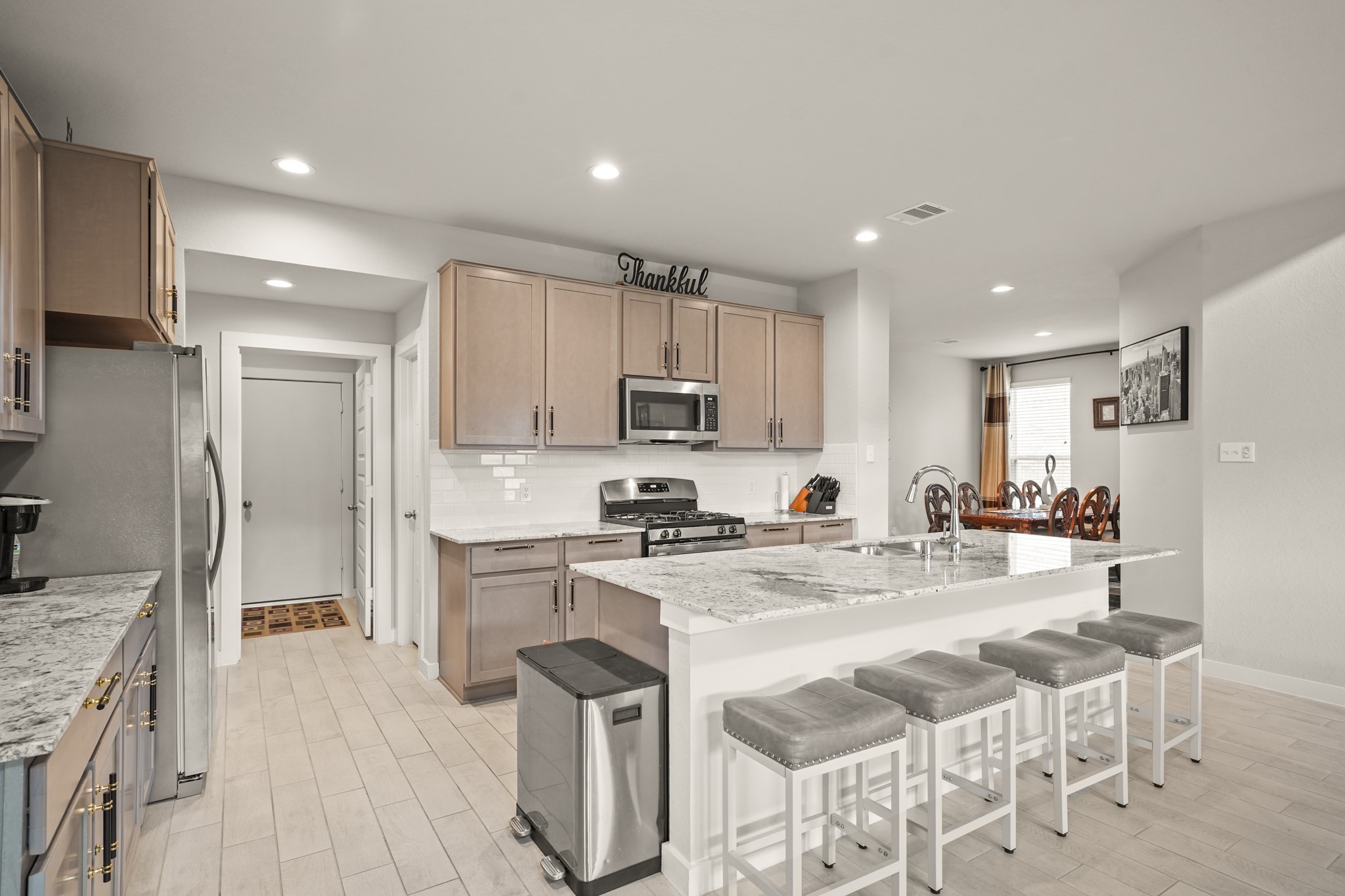18419 Windy Knl Way Houston, TX 77084 - Photo 34 of 50 a kitchen with a sink a stove a refrigerator and white cabinets with wooden floor