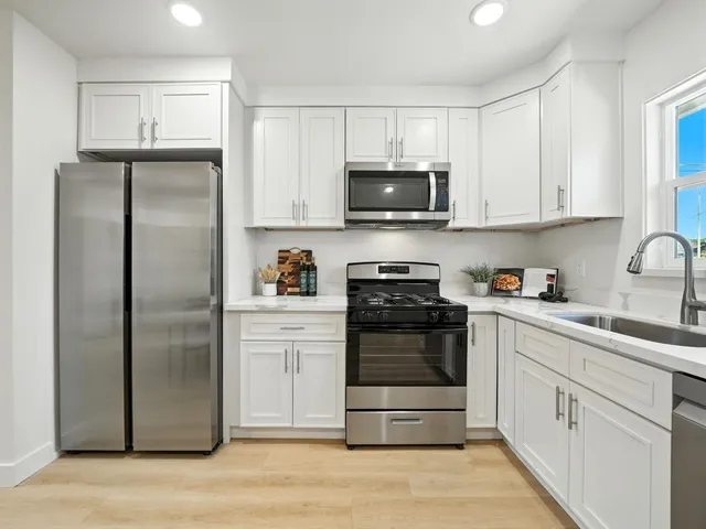a kitchen with white cabinets stainless steel appliances and a sink