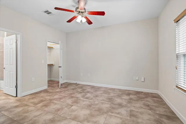 an empty room with windows and fan