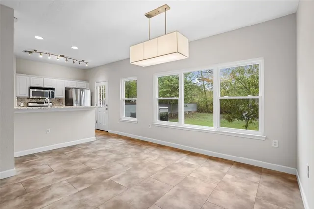 an empty room with windows and refrigerator