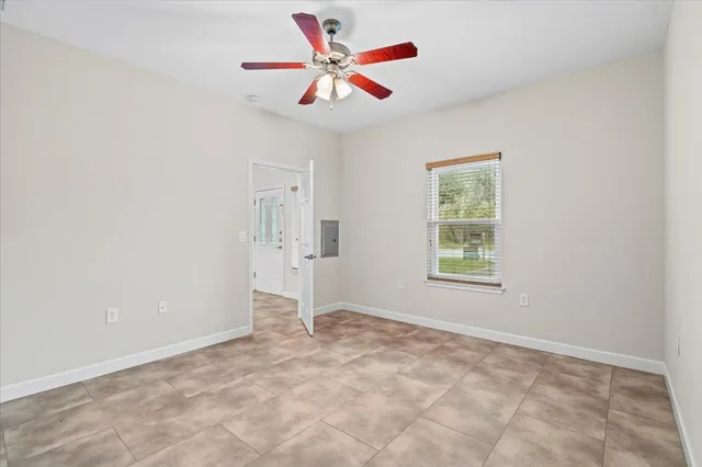 an empty room with ceiling fan and window