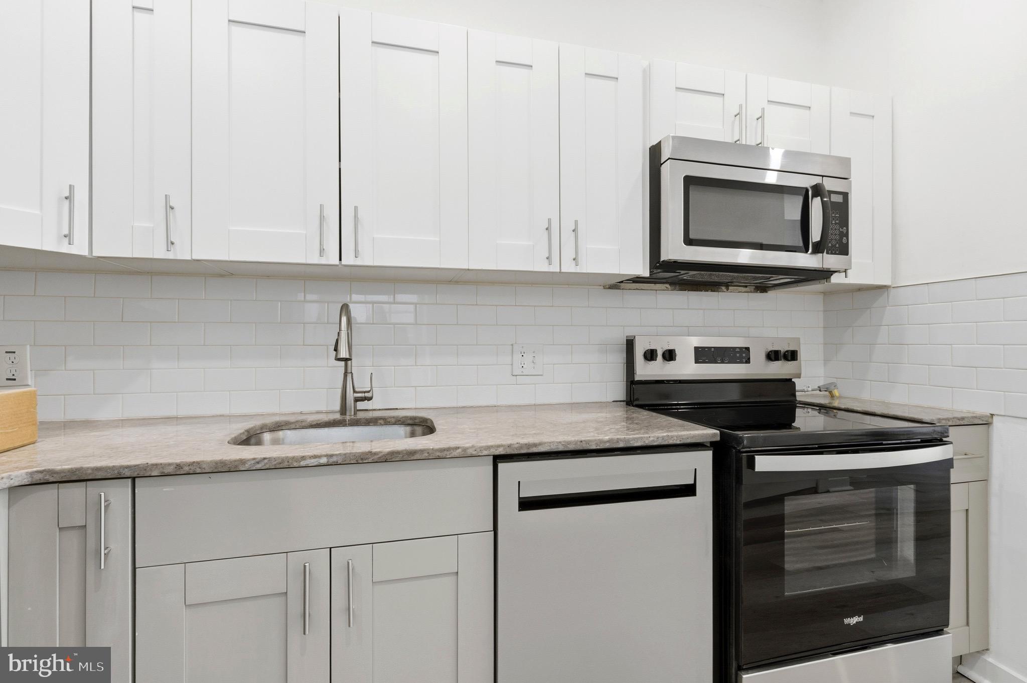 2150 North Franklin Street Philadelphia, PA 19122 - Photo 6 of 24 a kitchen with stainless steel appliances granite countertop white cabinets and a stove a oven with white countertops