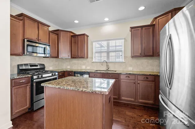 a kitchen with stainless steel appliances granite countertop a stove sink microwave and refrigerator