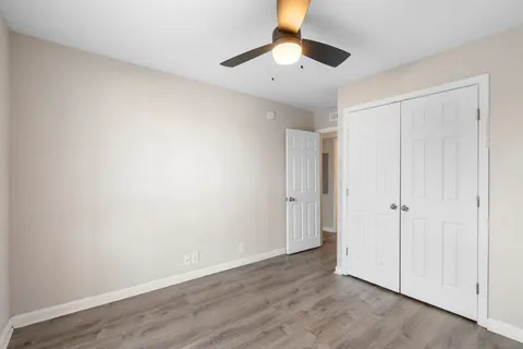 an empty room with wooden floor and ceiling fan