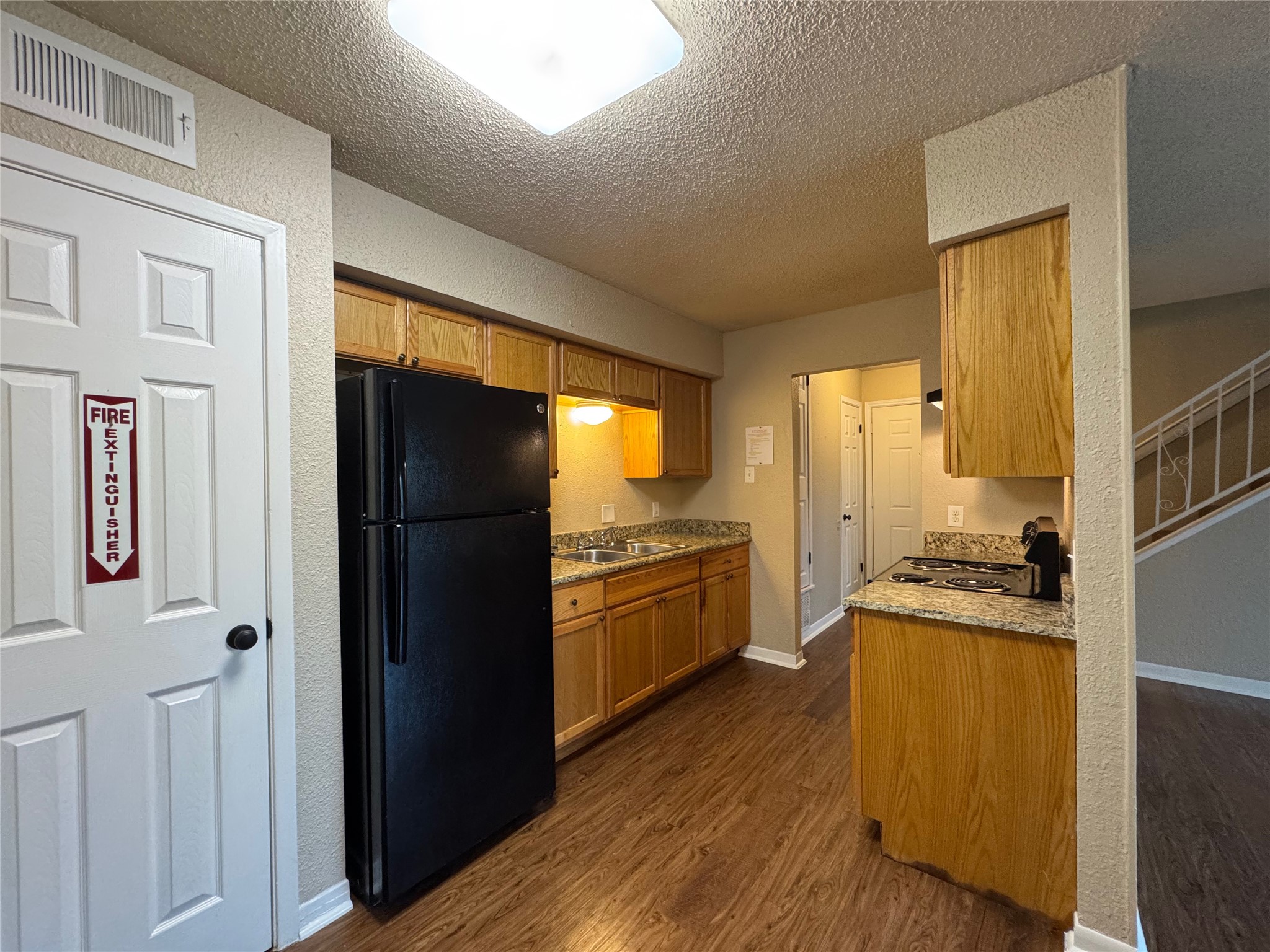 5006 West Wind Trail, Unit 101 Austin, TX 78745 - Photo 5 of 18 a kitchen with a refrigerator a stove top oven a wooden floor and cabinets