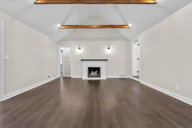a view of an empty room with wooden floor and a fireplace
