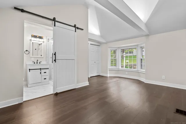an empty room with wooden floor cabinet and windows