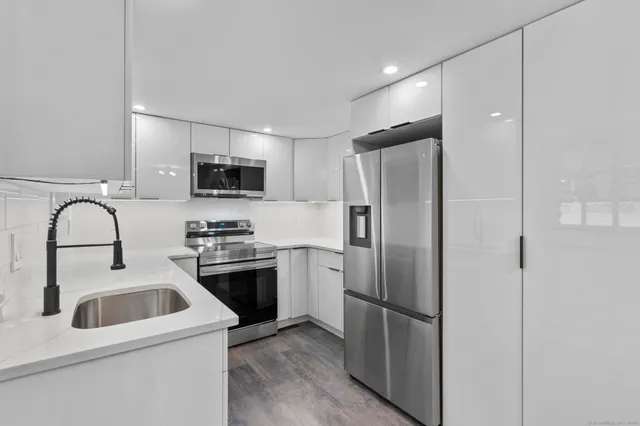 a kitchen with stainless steel appliances granite countertop a refrigerator a stove a sink and a microwave