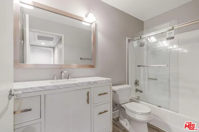 a bathroom with a granite countertop sink toilet mirror and a shower