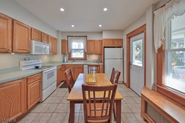 a kitchen with stainless steel appliances granite countertop a dining table chairs and a refrigerator
