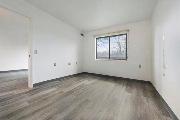 an empty room with wooden floor and windows