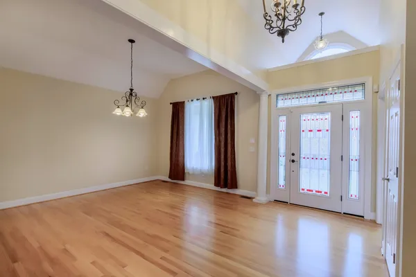 a view of a room with wooden floor chandelier and windows