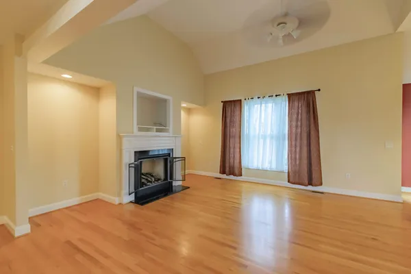 a view of empty room with wooden floor and fireplace