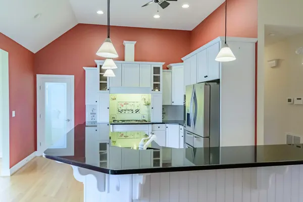 a kitchen with stainless steel appliances granite countertop a stove a refrigerator and a sink with wooden floor