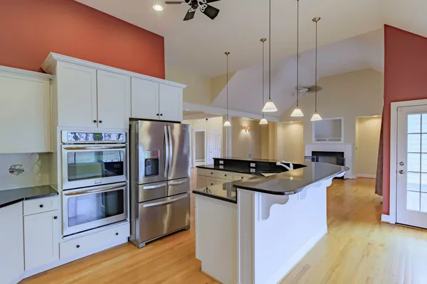 a kitchen with stainless steel appliances granite countertop a sink a stove and a wooden floor