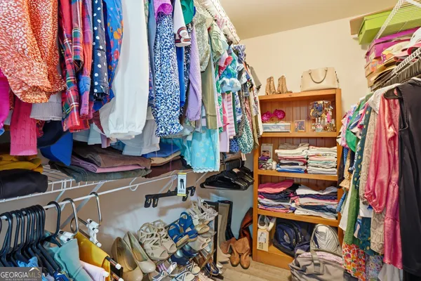 a view of walk in closet with clothes and shoes