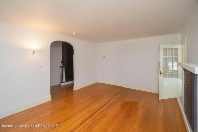 an empty room with wooden floor and a fireplace