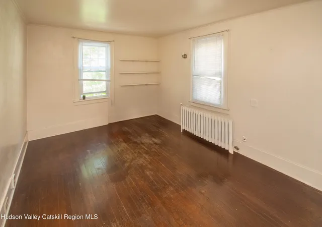 a view of an empty room with wooden floor and closet