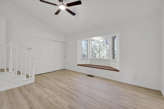 a view of an empty room with a window and wooden floor